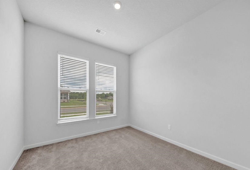 Carpeted room featuring two large windows with blinds, light gray walls, and a recessed ceiling light