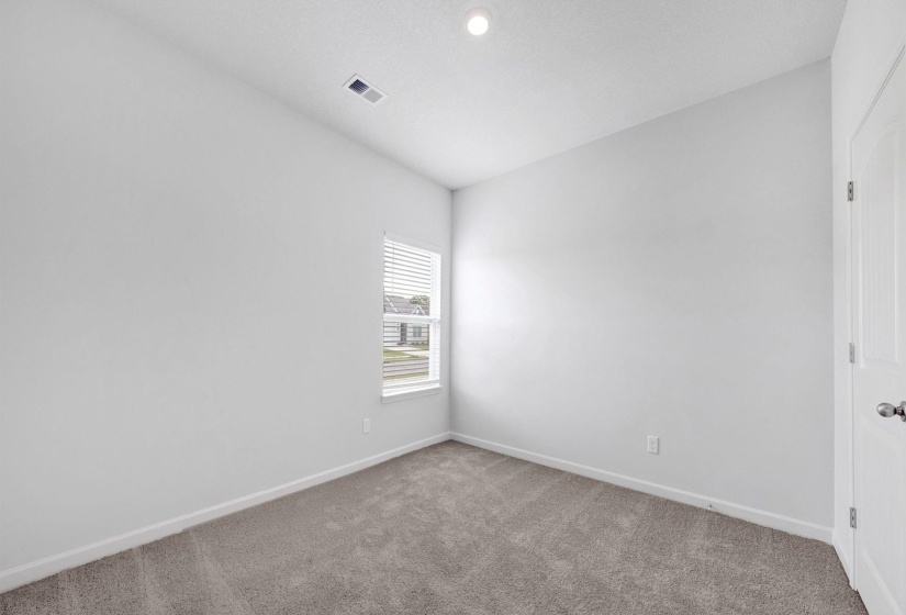 Bright room with neutral wall color, gray carpet flooring, white baseboards, and a window with horizontal blinds