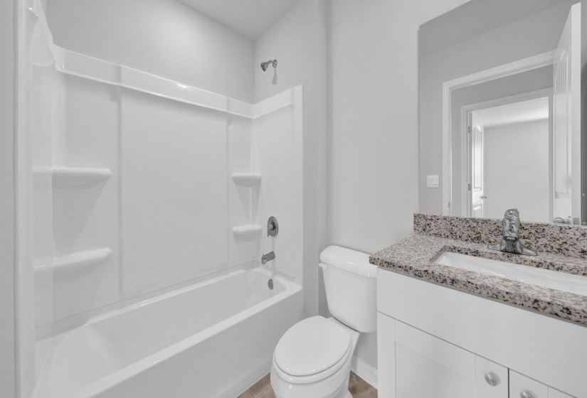 Bathroom featuring a white bathtub and shower surround, a white toilet, and a vanity with a granular countertop and an integrated sink
