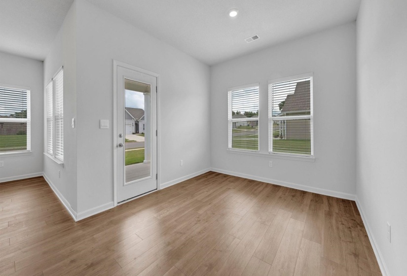 Open concept interior with light wood-finish flooring, recessed lighting, multiple windows, and a glass-paneled exterior door