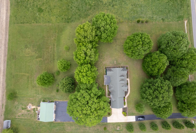 Expansive property featuring a central residence, extensive green space, mature trees, a paved driveway, and an additional outbuilding