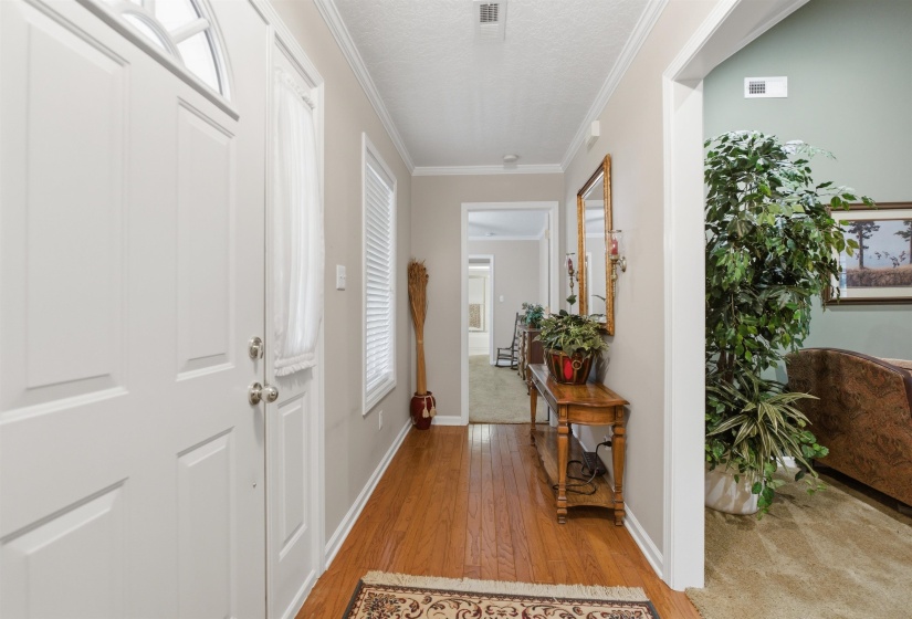 Entryway featuring wood-finish flooring, white paneled doors with arch transom, and crown molding