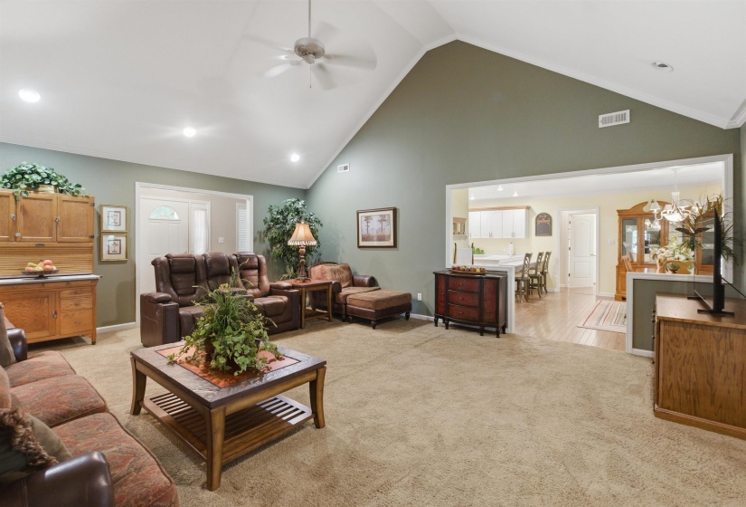Spacious living area featuring a vaulted ceiling with a ceiling fan, recessed lighting, and soft carpeting