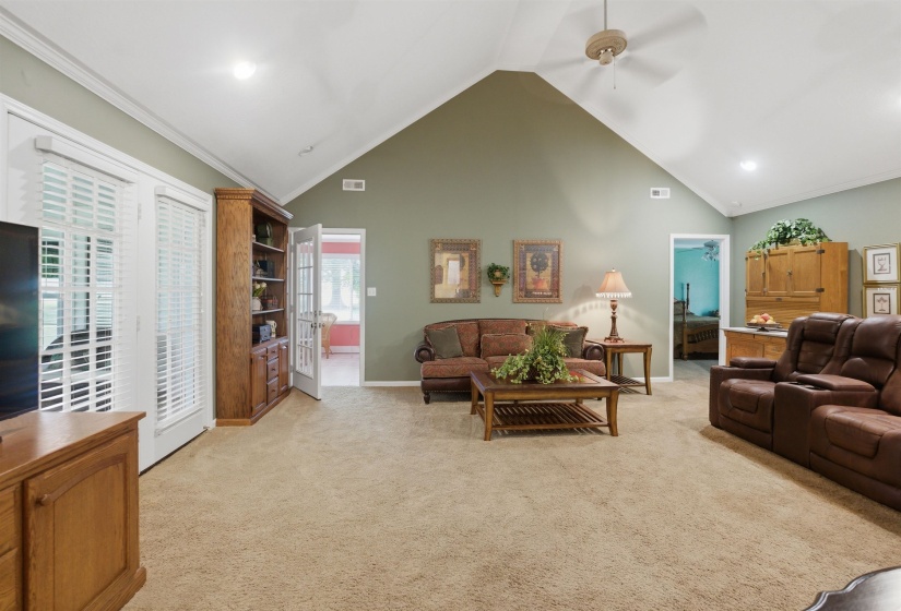 Spacious living area featuring a vaulted ceiling and light-toned carpeting