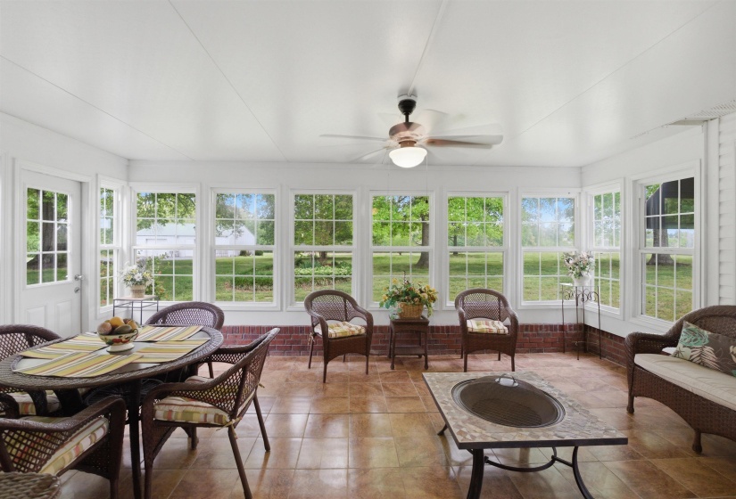 Sunroom with extensive window array, ceramic tile flooring, a white paneled ceiling, and a ceiling fan