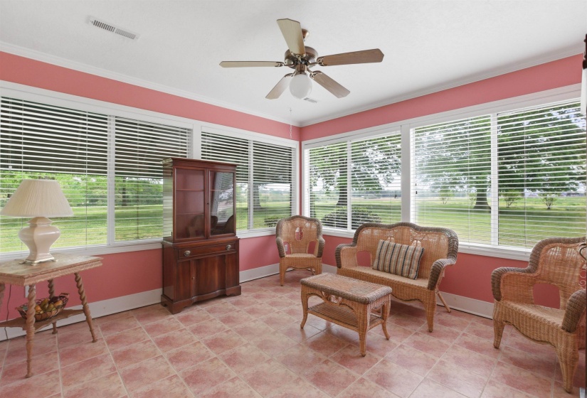 Sunroom featuring extensive window-lines, white trim, and a ceiling fan