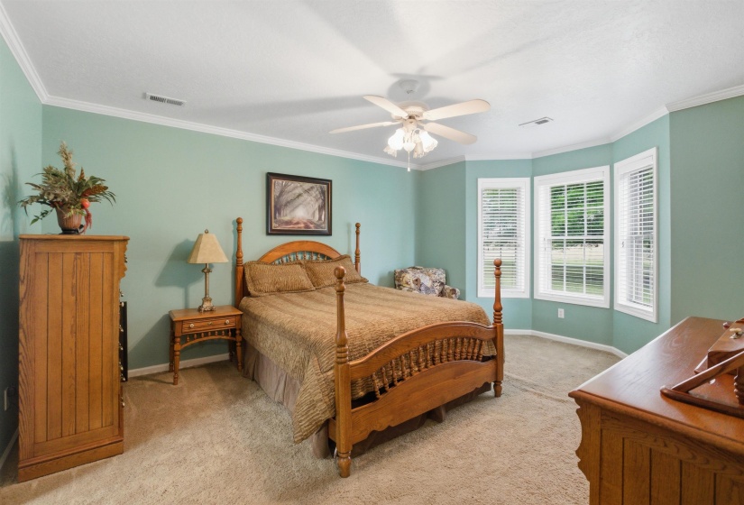 Bedroom featuring a bay window, crown molding, a ceiling fan, and carpeted flooring