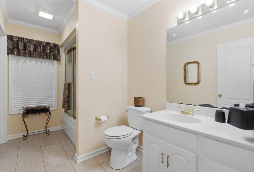 Bathroom featuring a white vanity with integrated sink, gold-toned faucet, and a large wall-mounted mirror