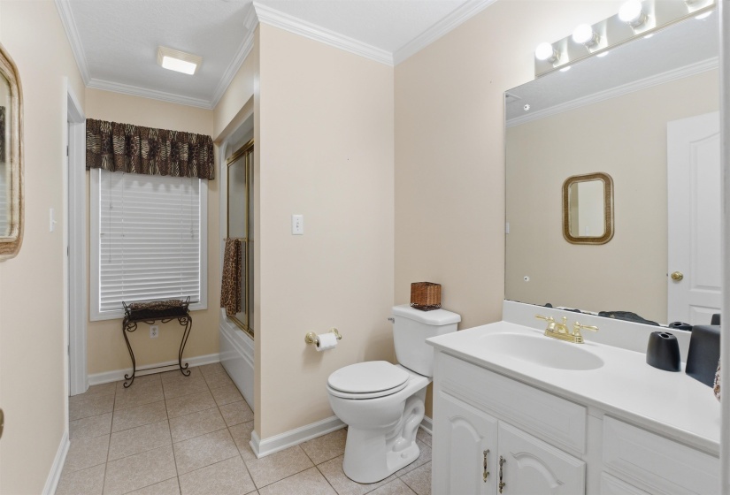 Bathroom featuring a single vanity with an integrated sink, polished brass faucet, and overhead lighting