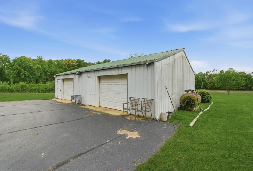 Metal utility building featuring a green pitched roof, two white garage doors, and two white entry doors