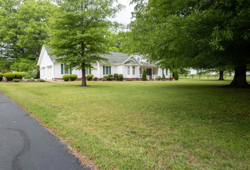 White single-story residence featuring a covered front porch with white columns, green window shutters, and a two-car garage
