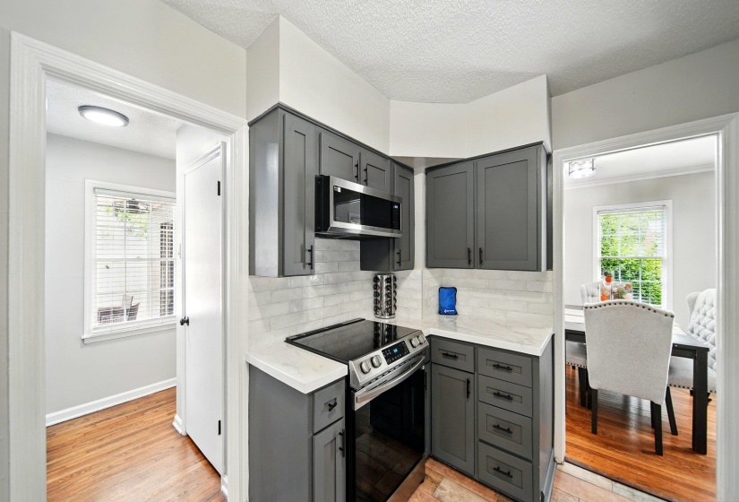 Kitchen with gray cabinetry, stainless steel appliances, light wood-style flooring, a textured ceiling, and decorative backsplash
