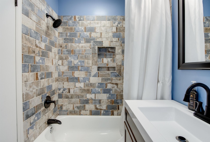 Bathtub and shower combination featuring distressed subway tile surround with integrated niche
