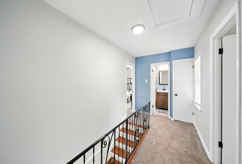 Hallway featuring light colored carpet and an upstairs landing