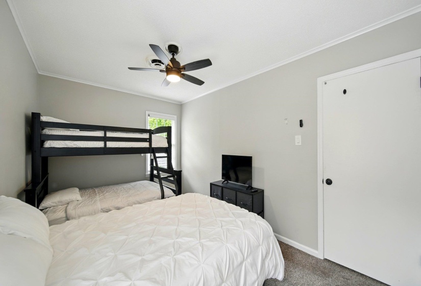 Carpeted bedroom with crown molding and a ceiling fan