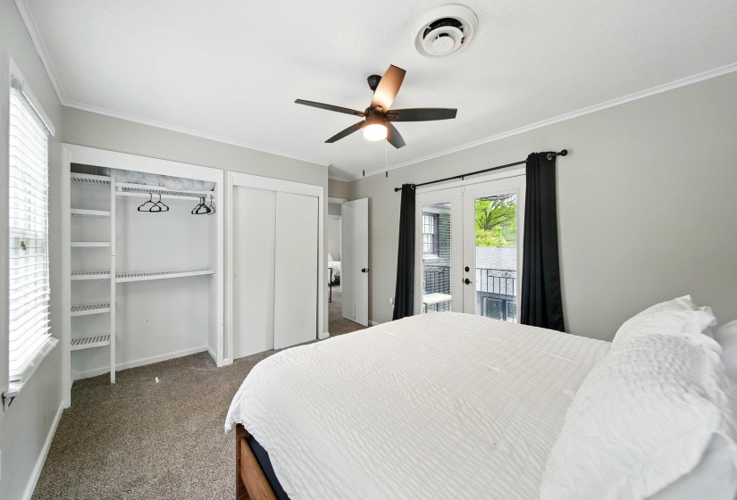 Bedroom with two closets, dark carpet, access to exterior, french doors, and a ceiling fan