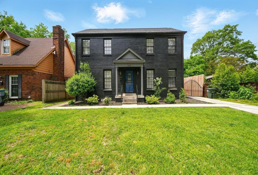 Colonial house featuring a gate, brick siding, and a chimney