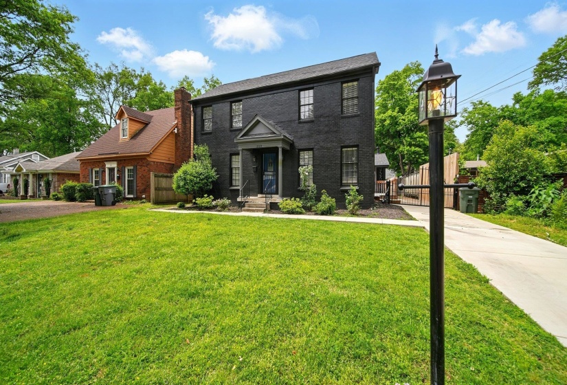 Colonial house featuring brick siding, a chimney, and a gate