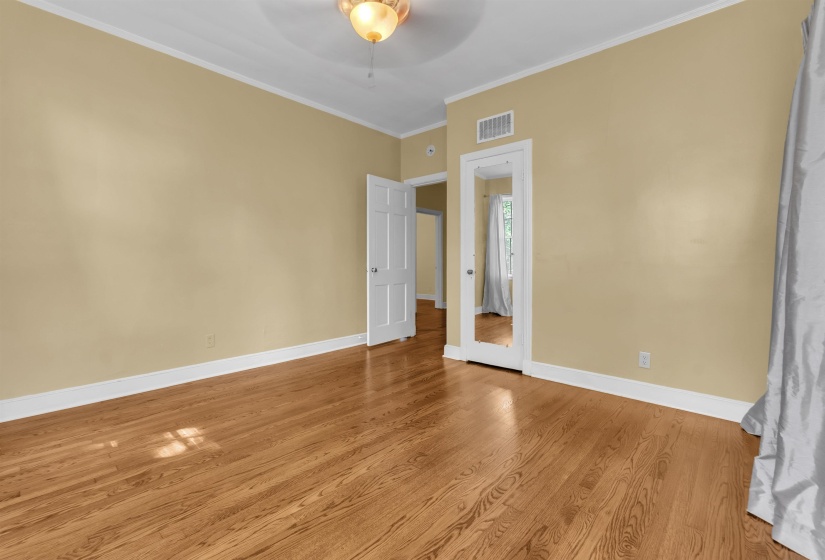 Spacious room featuring wood-finish flooring, light tan walls, and white baseboards