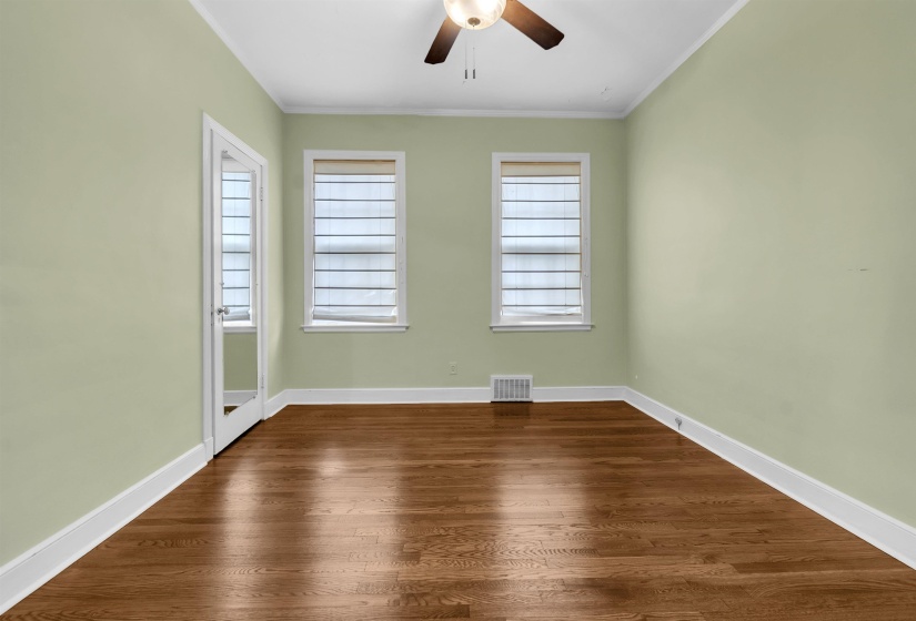 Room featuring wood-finish flooring, light green walls, and white trim