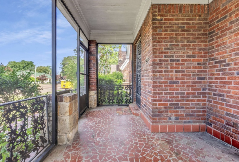 Screened porch featuring a mosaic tile floor, brick exterior walls, and ornate metal railings