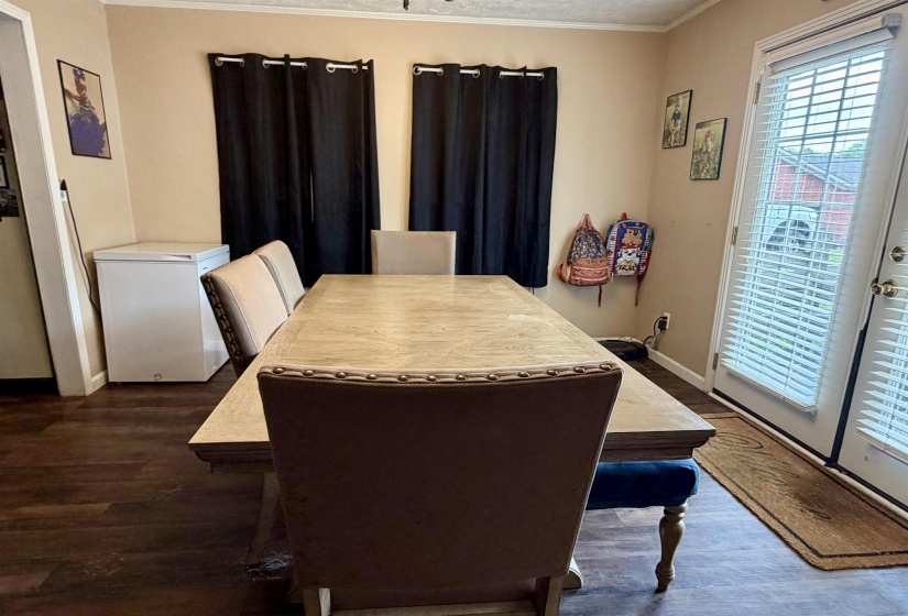 Dining area featuring wood-finish flooring, neutral wall tones, and double French doors with blinds