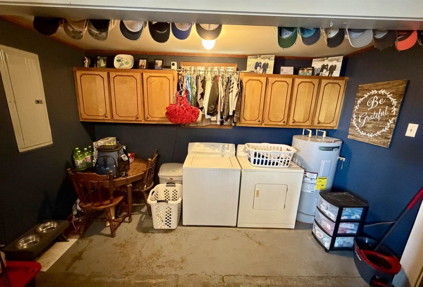 Dedicated utility space featuring overhead wood-finish cabinetry, a full-size washer and dryer, and a water heater