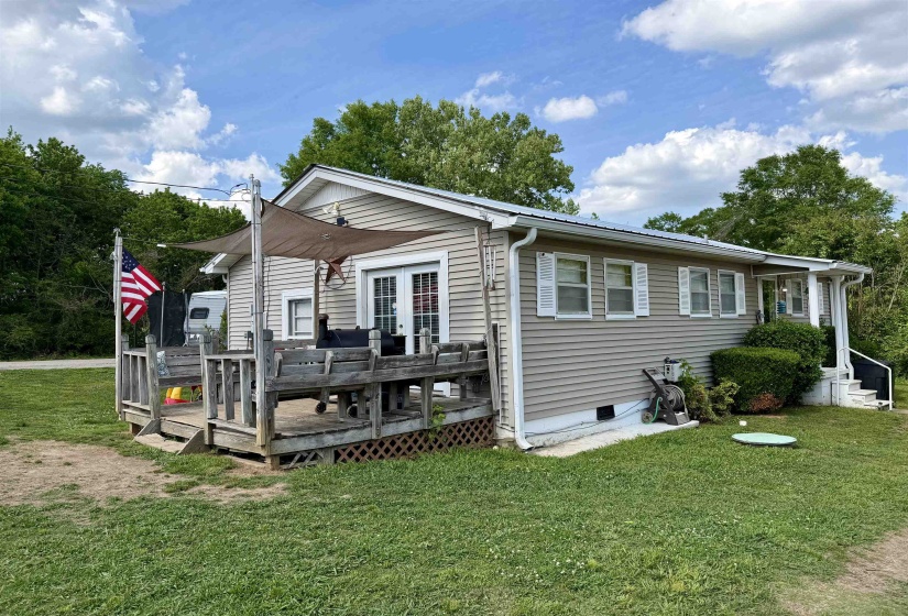Exterior featuring horizontal siding, white window shutters, and a wooden deck with a shade sail