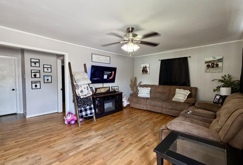 Living area featuring wood-finish flooring, light gray walls, and white crown molding