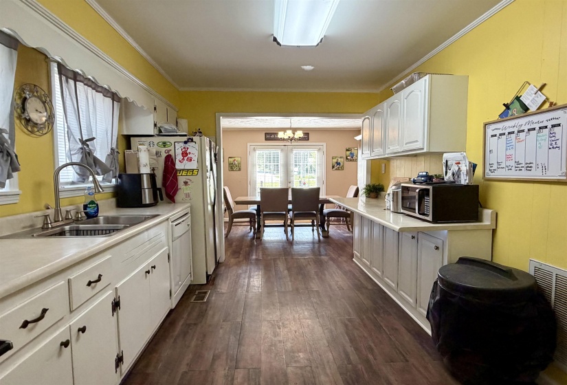 Galley kitchen featuring wood-finish flooring, white cabinetry, and light-toned countertops