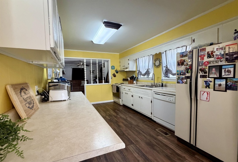Kitchen featuring wood-finish flooring, white cabinetry, integrated dishwasher, and a double basin sink