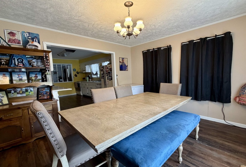 Dining area featuring wood-finish flooring, a chandelier, and an open doorway to the kitchen