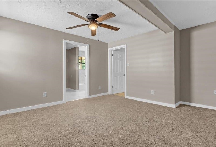 Carpeted room featuring a ceiling fan with light fixture, neutral wall paint, white trim, and two doorways
