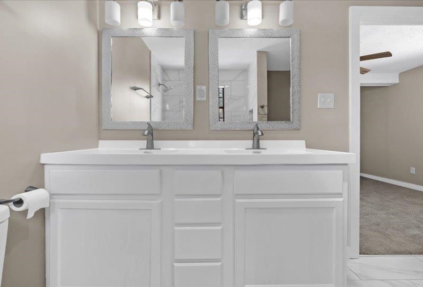 Bathroom featuring a dual vanity with white cabinetry, white countertop, and two framed mirrors