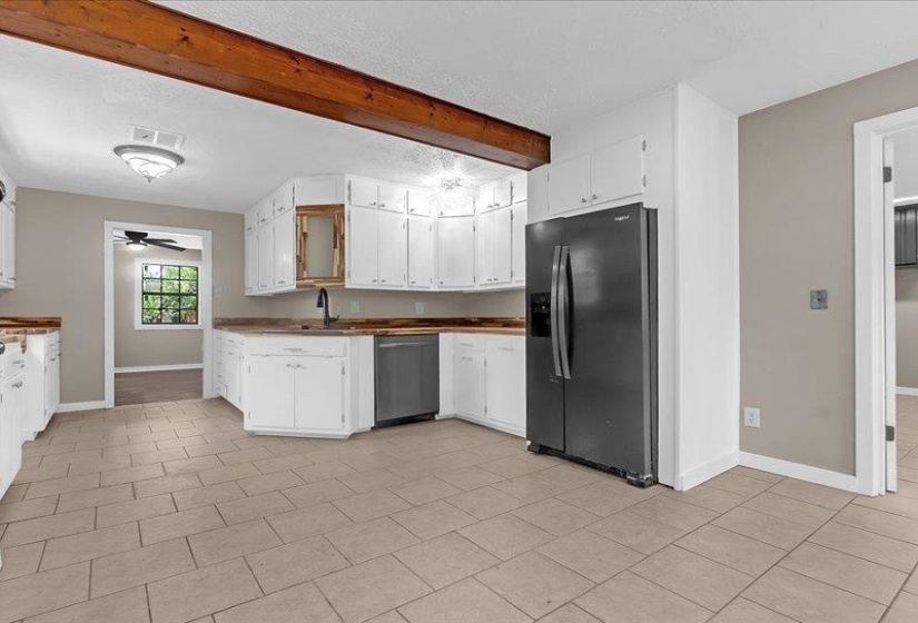 Kitchen featuring a dark stainless steel French door refrigerator, white cabinetry, dark wood-finish countertops, a dark stainless steel dishwasher, and tile flooring