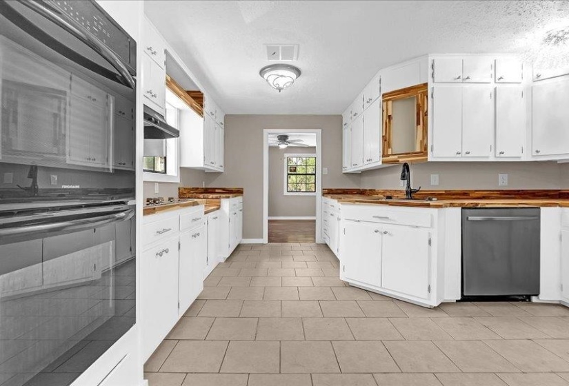Kitchen featuring white cabinetry, wood-finish countertops, stainless steel appliances, and tile flooring
