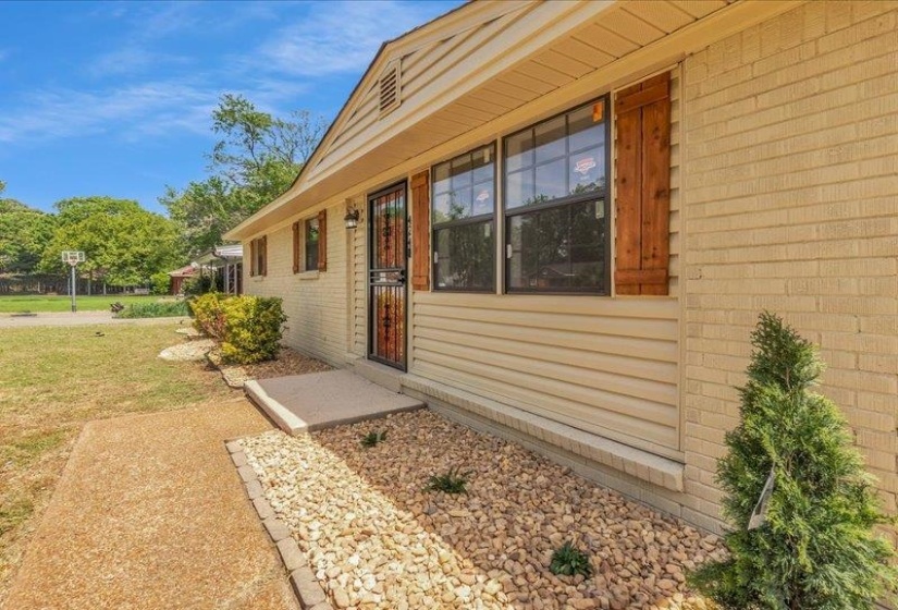 Exterior featuring light-colored brick, horizontal siding, and a gabled roofline