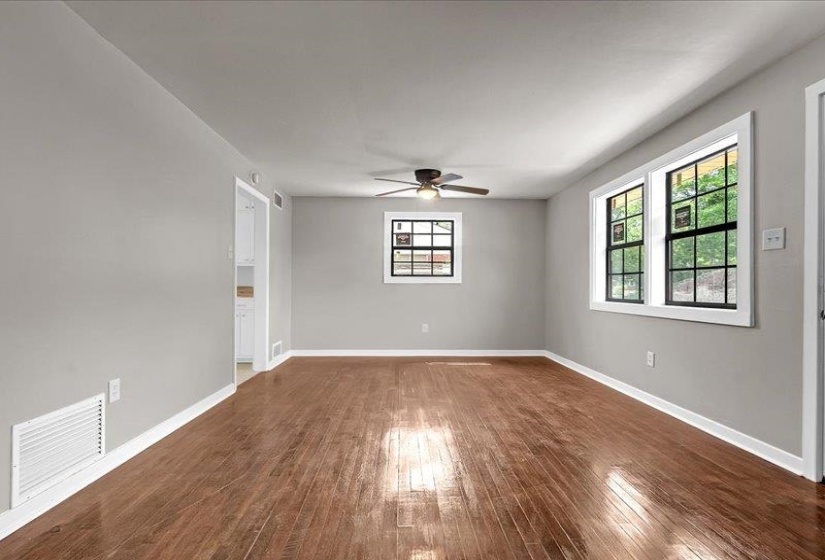 Spacious room featuring wood-finish flooring, light grey walls, white trim, and multiple black-framed windows