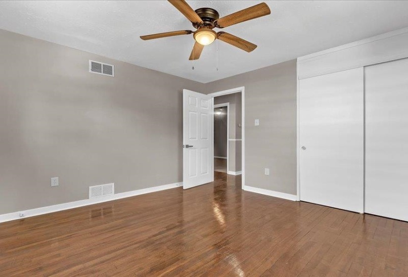 Room featuring wood-finish flooring, a ceiling fan with light fixture, and white trim