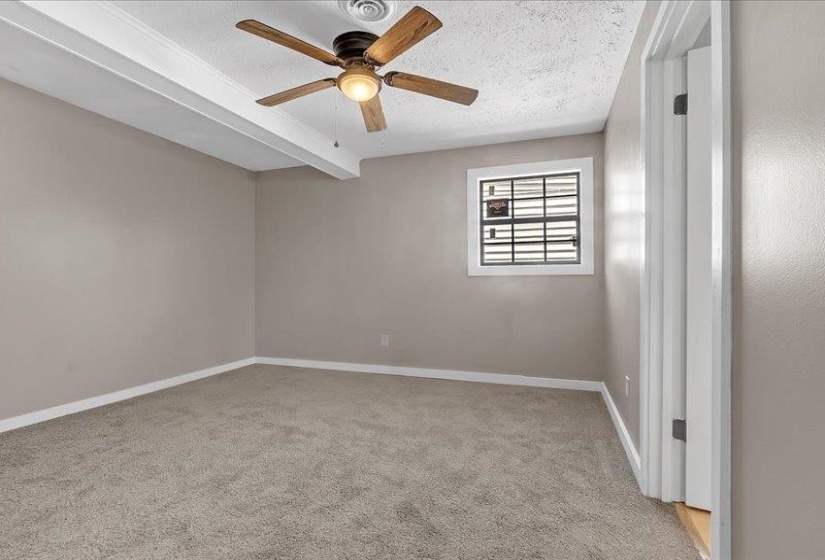 Carpeted interior space featuring a ceiling fan with integrated lighting, a window with horizontal blinds, and a white trim package
