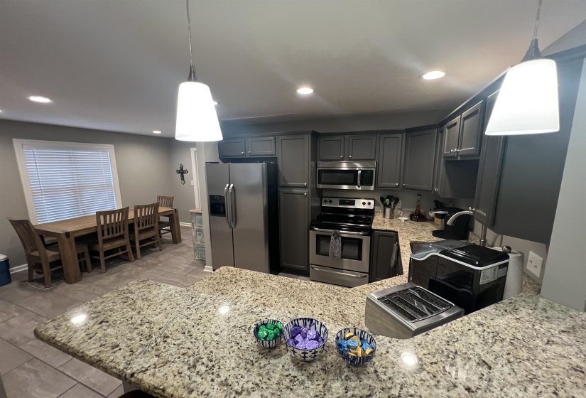 Kitchen with stainless steel appliances, recessed lighting, light stone counters, and hanging light fixtures