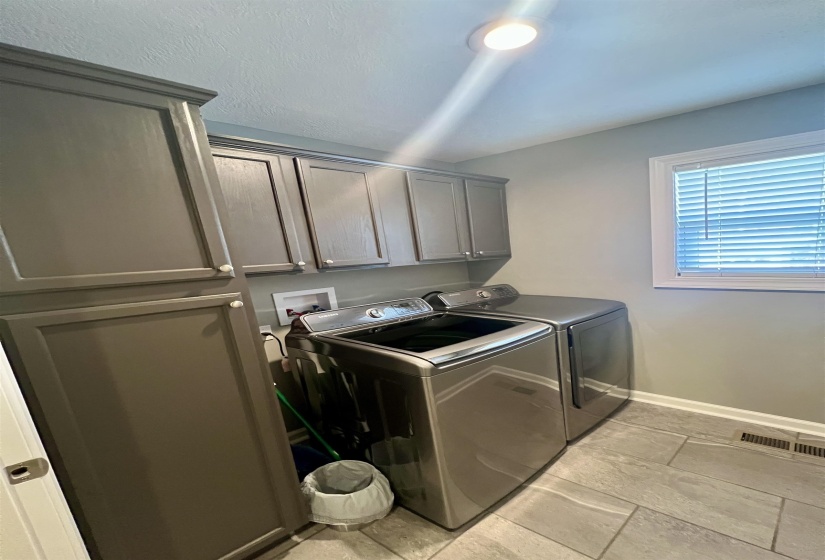 Laundry area with cabinet space, washing machine and dryer, and stone tile floors