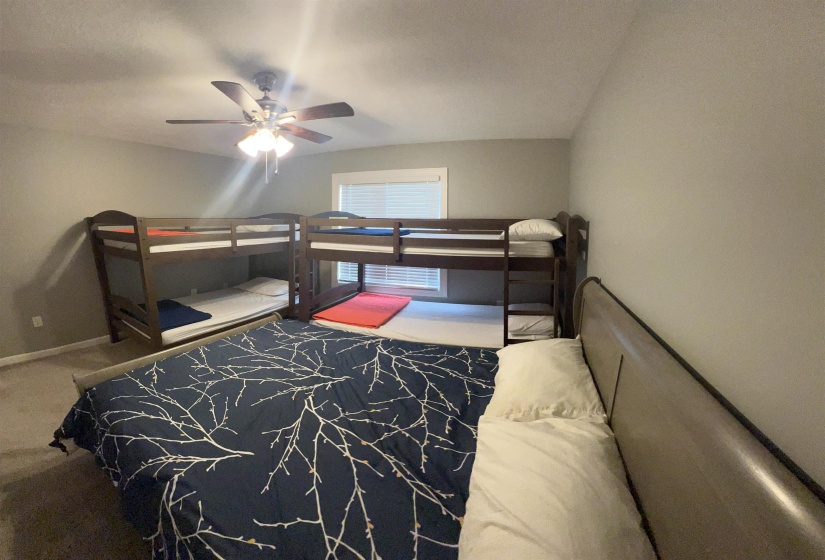 Carpeted bedroom featuring ceiling fan and baseboards