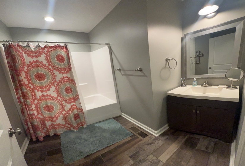 Bathroom with dark wood finished floors, vanity, and shower / bath combo with shower curtain