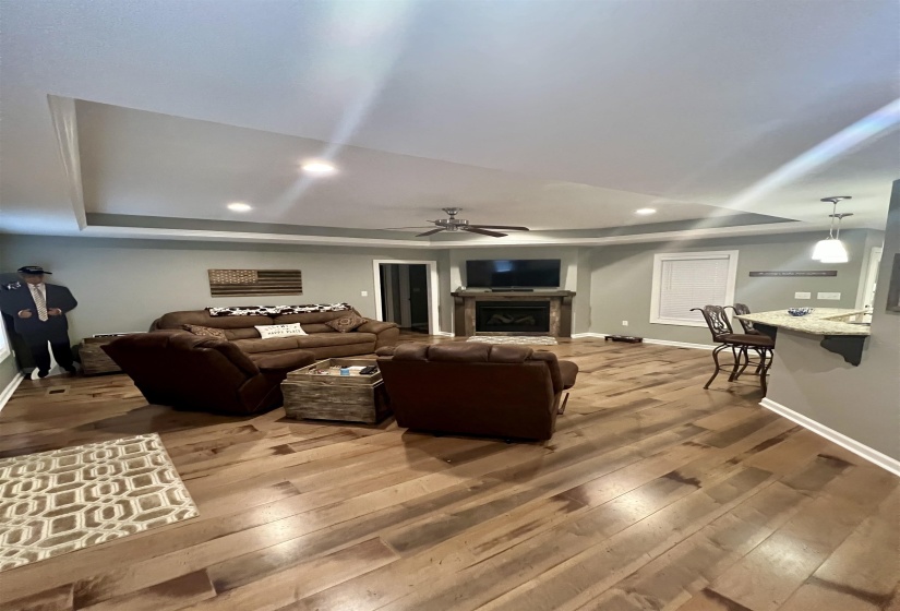 Living area featuring a raised ceiling, a fireplace, wood-type flooring, recessed lighting, and a ceiling fan