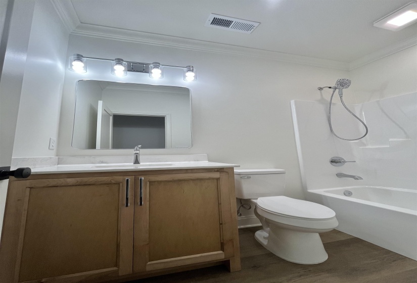 Full bath with shower / bath combination, vanity, crown molding, and dark wood finished floors