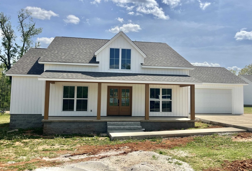 Modern farmhouse with a shingled roof, covered porch, concrete driveway, and a garage