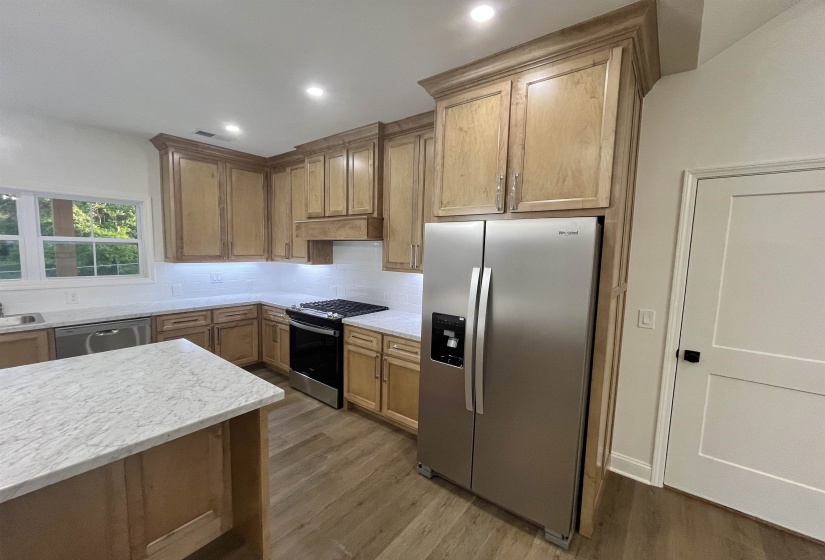 Kitchen with stainless steel appliances, backsplash, dark wood-style flooring, recessed lighting, and light stone counters