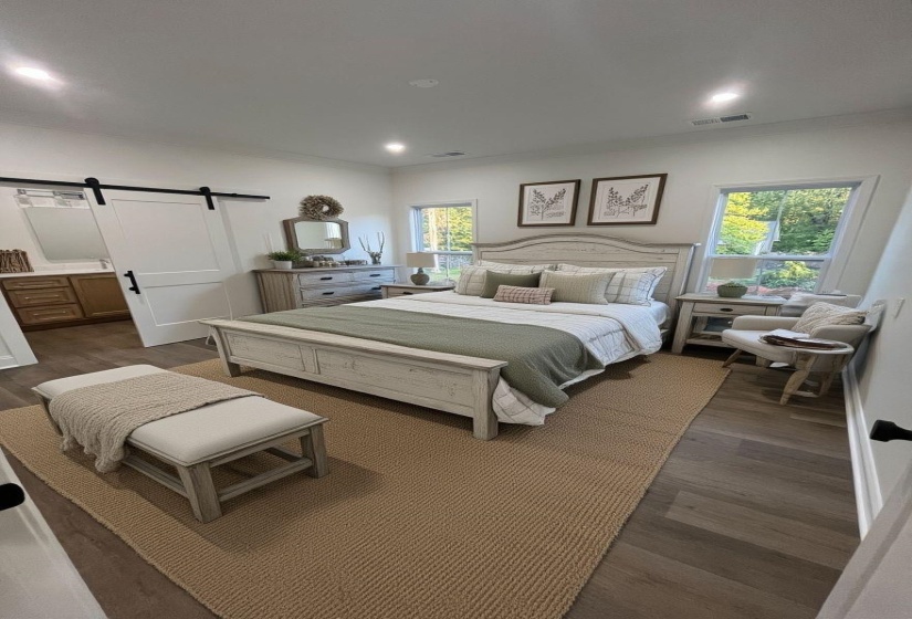 Spacious bedroom with wood-finish flooring and recessed lighting