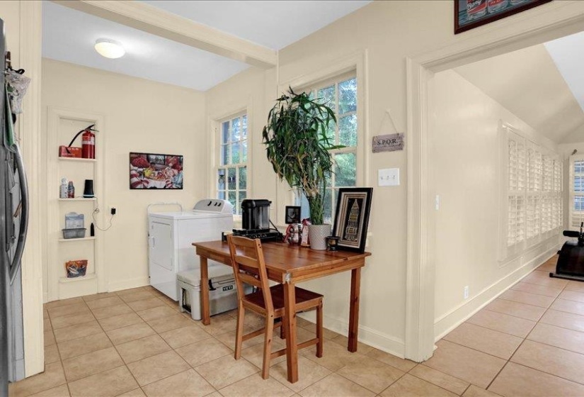 Kitchenette area featuring light-toned tile flooring and a built-in wall niche with shelving. Leading to the big bonus room.  More space.  YES!